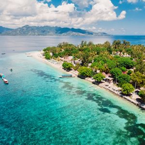 Tropical island with beach and turquoise transparent ocean, aerial view. Gili islands